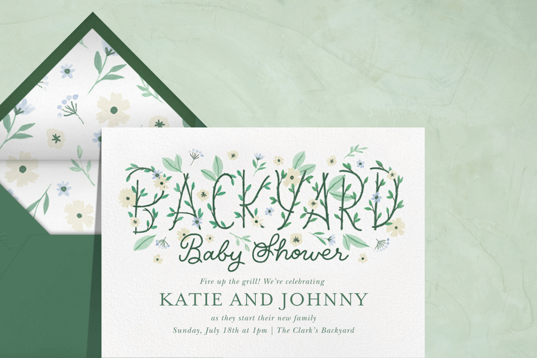 A baby shower invitation featuring “Backyard Baby Shower” spelled in hand lettering with flowers growing out of the letters.